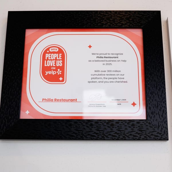 A framed Yelp "People Love Us" award for Philia Restaurant, dated November 1, 2025.